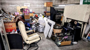 Property management junk removal service clearing out hoarded items, bulk waste, and old furniture from an apartment parking structure.